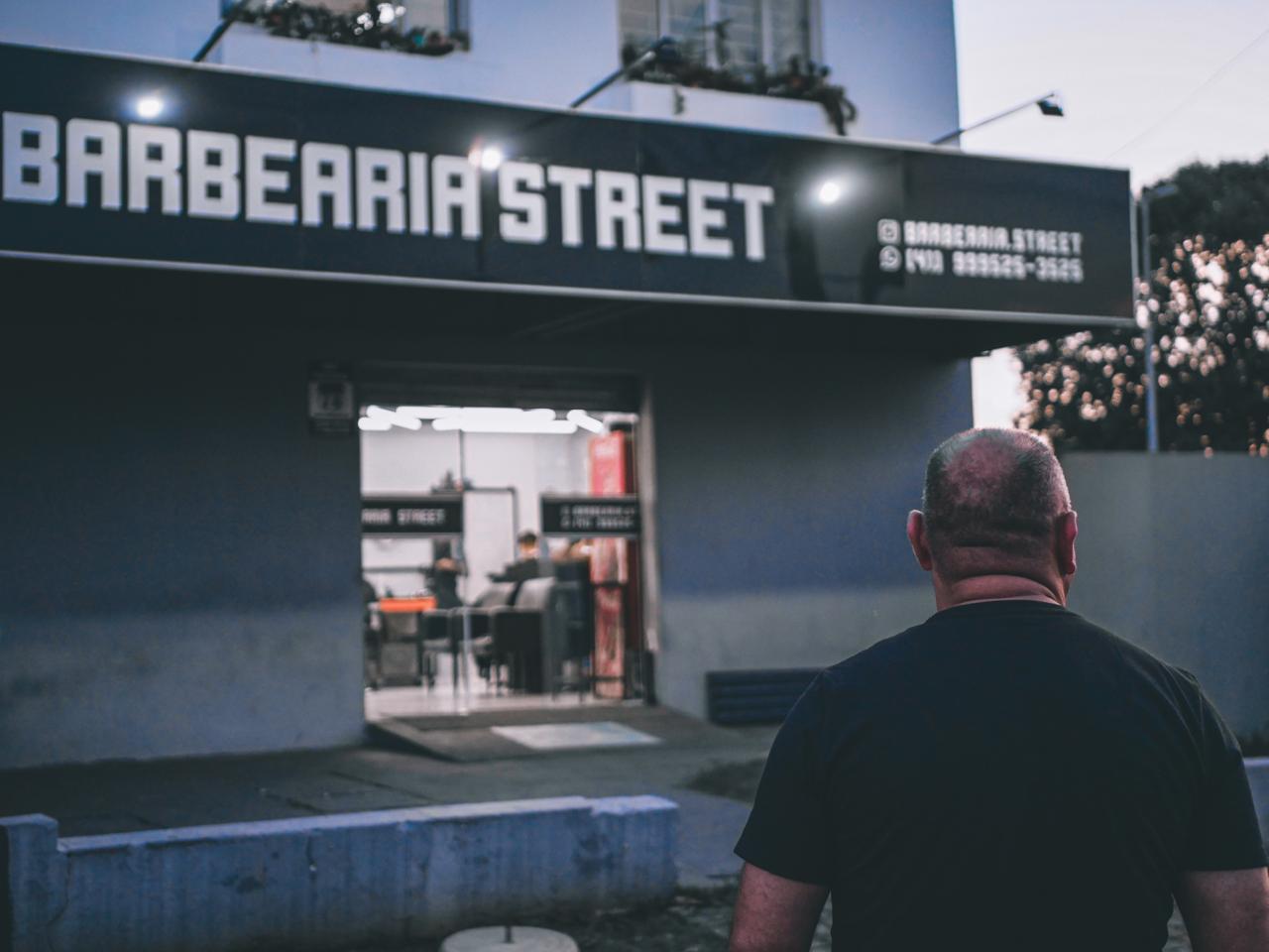 Fachada iluminada da Barbearia Street Cut, na Fazendinha, Curitiba